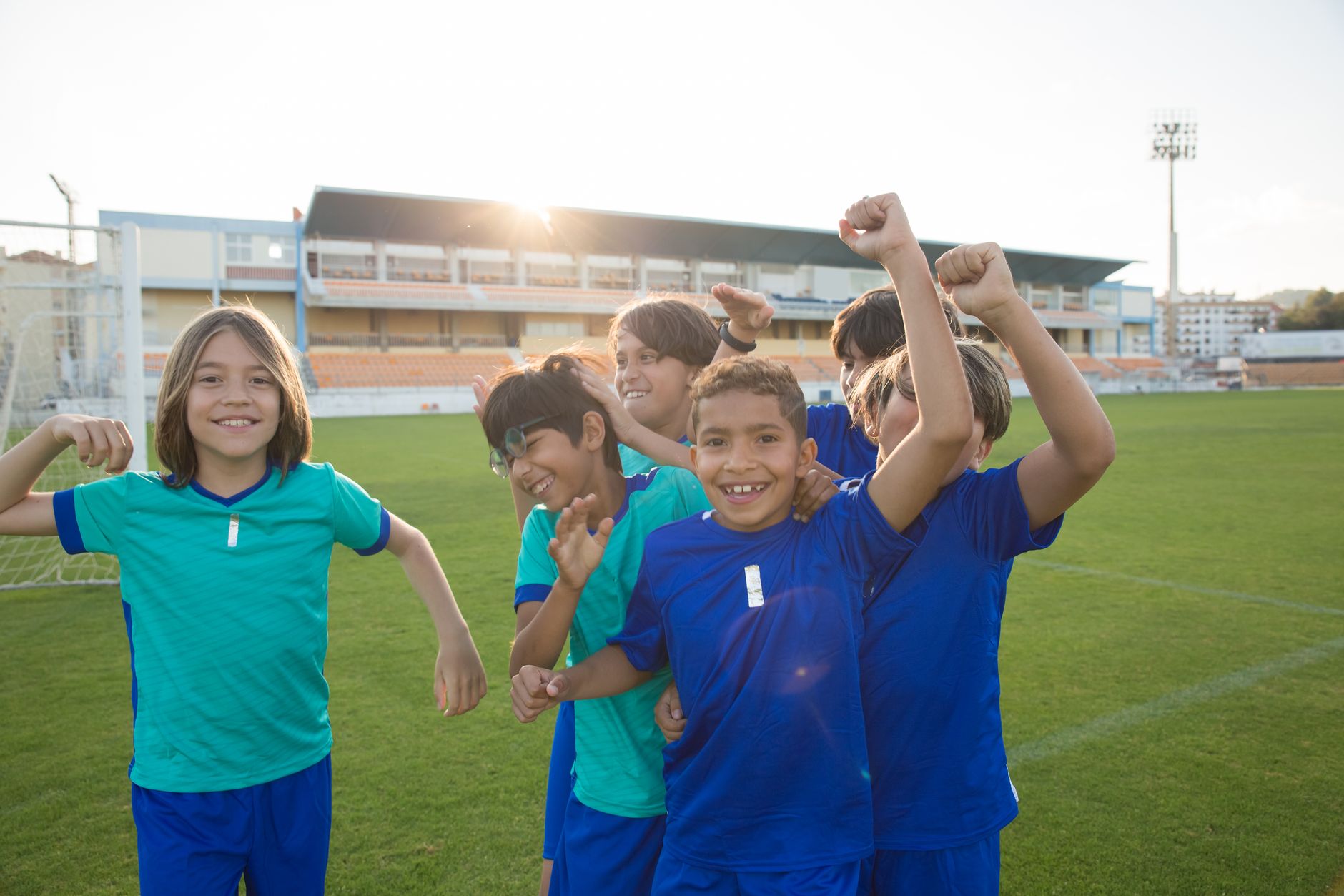 Happy group of children celebrating victory on a soccer field in Portugal.