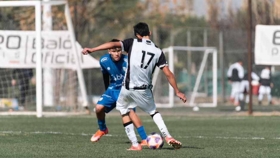 Two soccer players compete for possession during a daytime match outdoors.