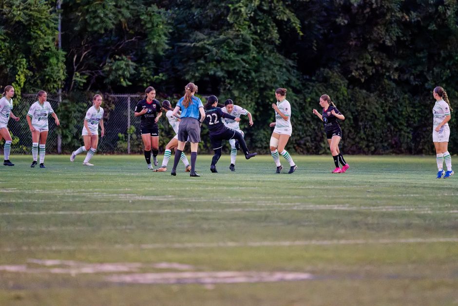 Female soccer teams competing fiercely on a lush outdoor field.