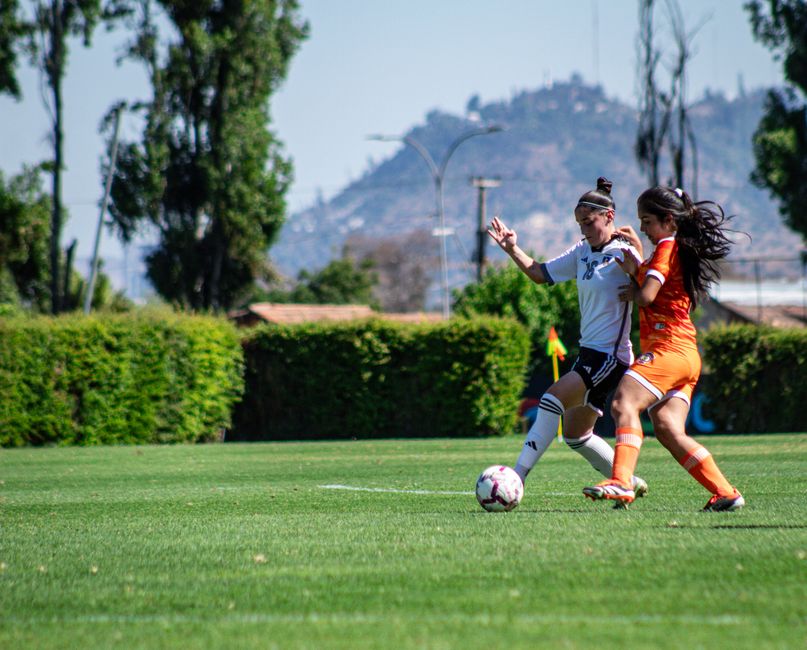 Intense soccer match between female athletes on a green field in Chile.
