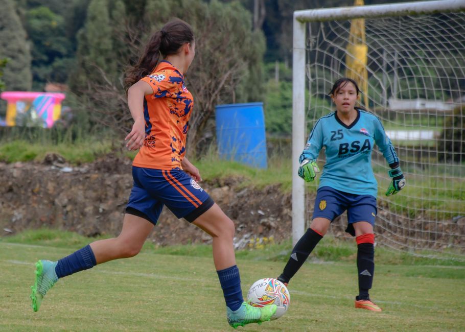 Two young female athletes engaged in a lively soccer match outdoors.