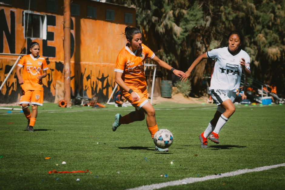 Exciting women's football match with players in action on a sunny day in Chile.