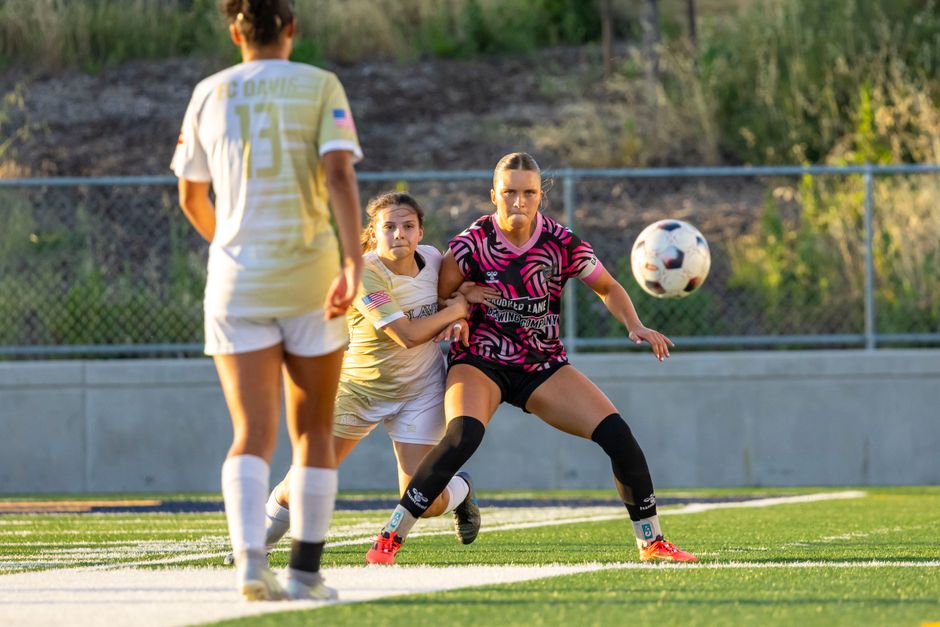 Intense soccer match with female players in action during daylight.