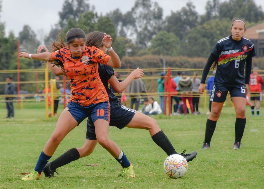 Intense action during a women's soccer match with players battling for the ball on the pitch.