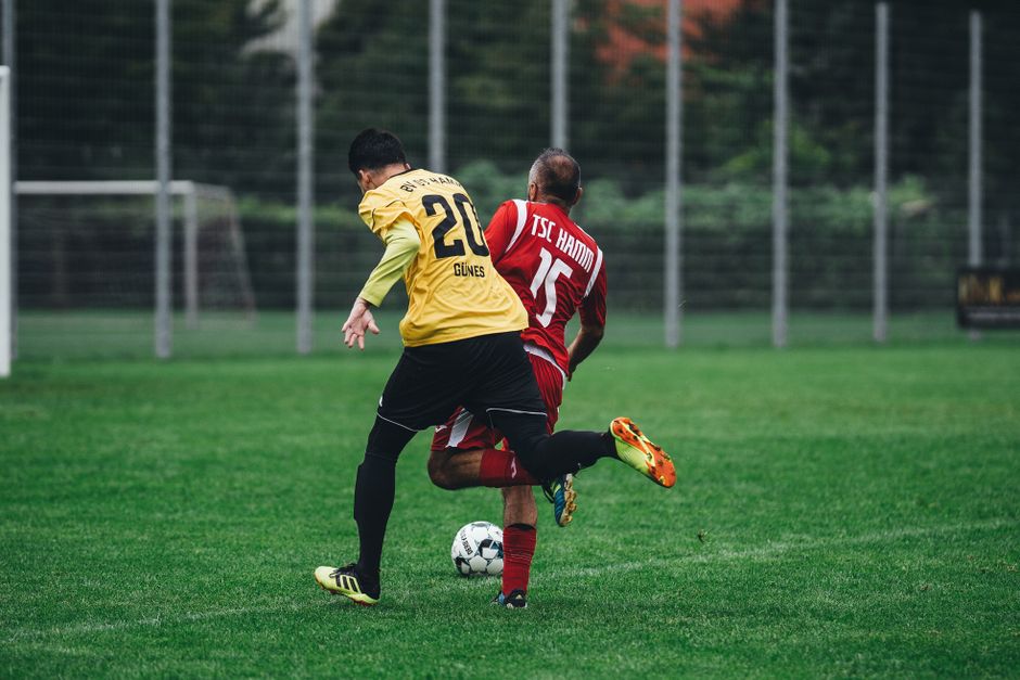 Two soccer players in action on a vibrant green field during a daytime match.