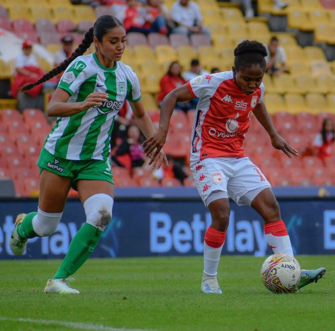 Two female soccer players in action during a competitive match at a stadium.
