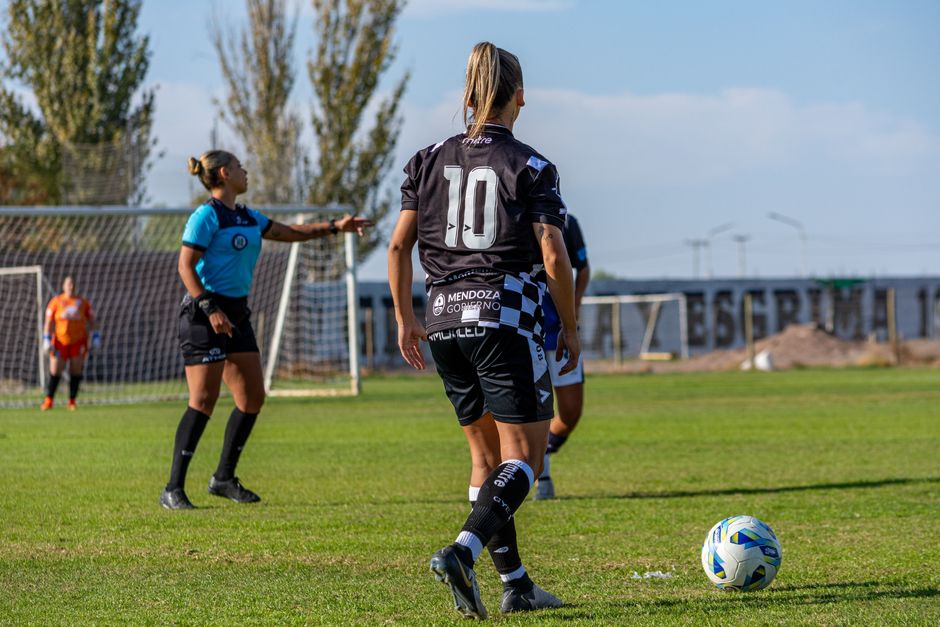Competitive women's soccer match being played outdoors on a sunny day.