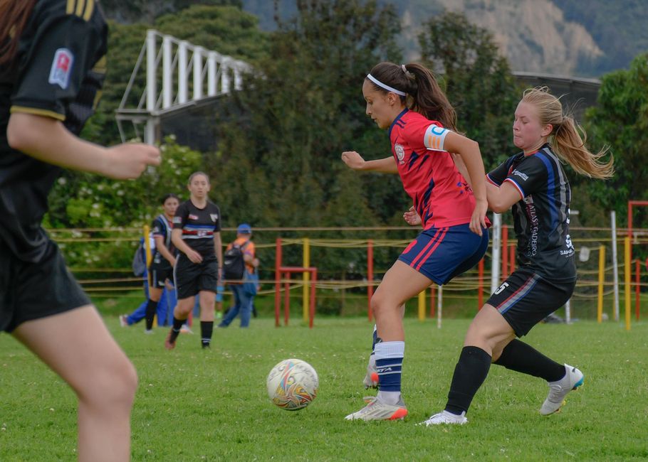 Female soccer players competing on a vibrant green field, showcasing teamwork and sportsmanship.