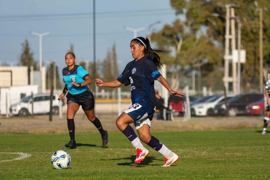 Two female soccer players in action during a football match on a sunny day.