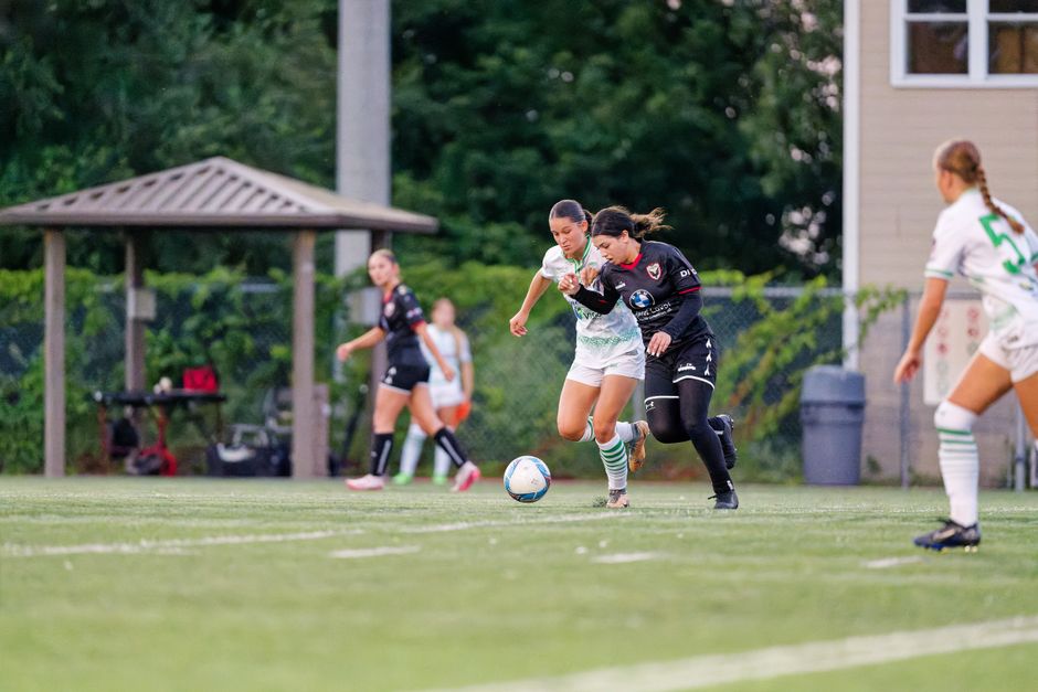 Female players compete in a soccer match, showcasing teamwork and athleticism.