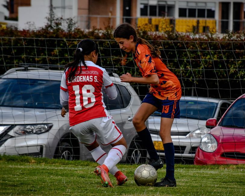 Two women soccer players in action during a match on a grass field, showcasing skill and competition.