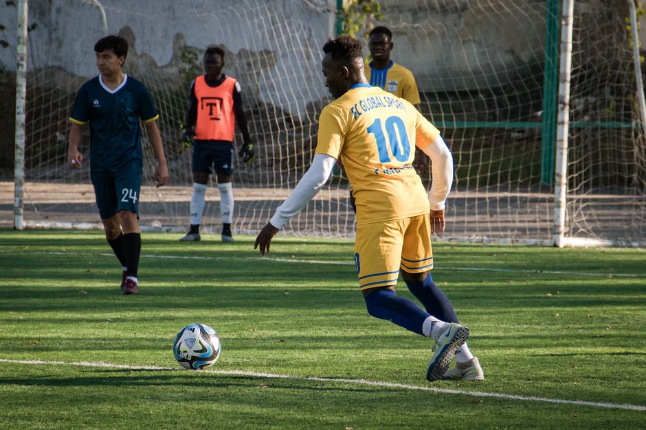 Soccer game at outdoor field in Almaty, Kazakhstan with players in action.