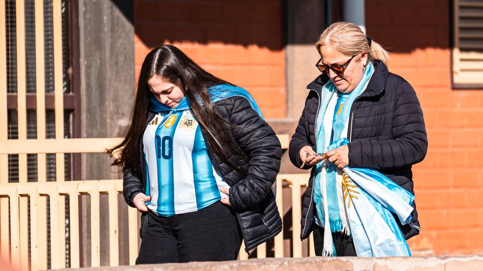 Two women in Argentine football jerseys outdoors, showing team spirit.
