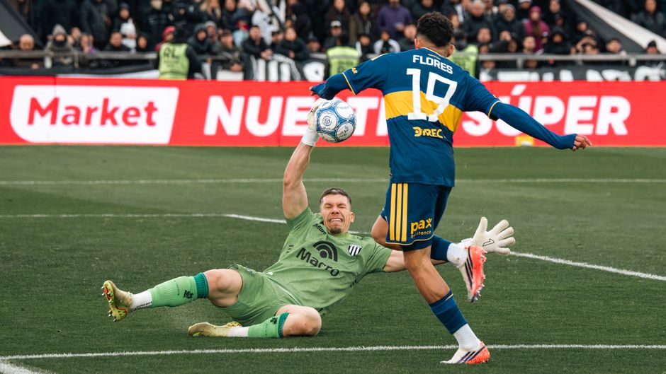 Intense soccer match moment with goalkeeper attempting save during game.